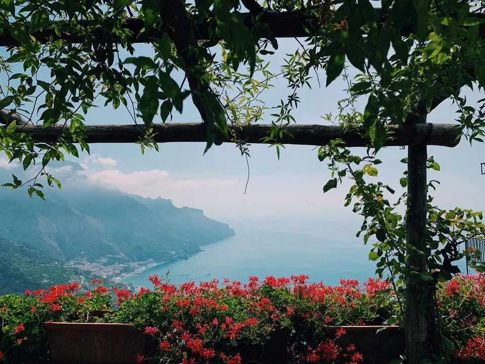 Blick von oben auf Ravello, einen Ort an der Amalfiküste, mit Terrassengärten und dem Meer im Hintergrund