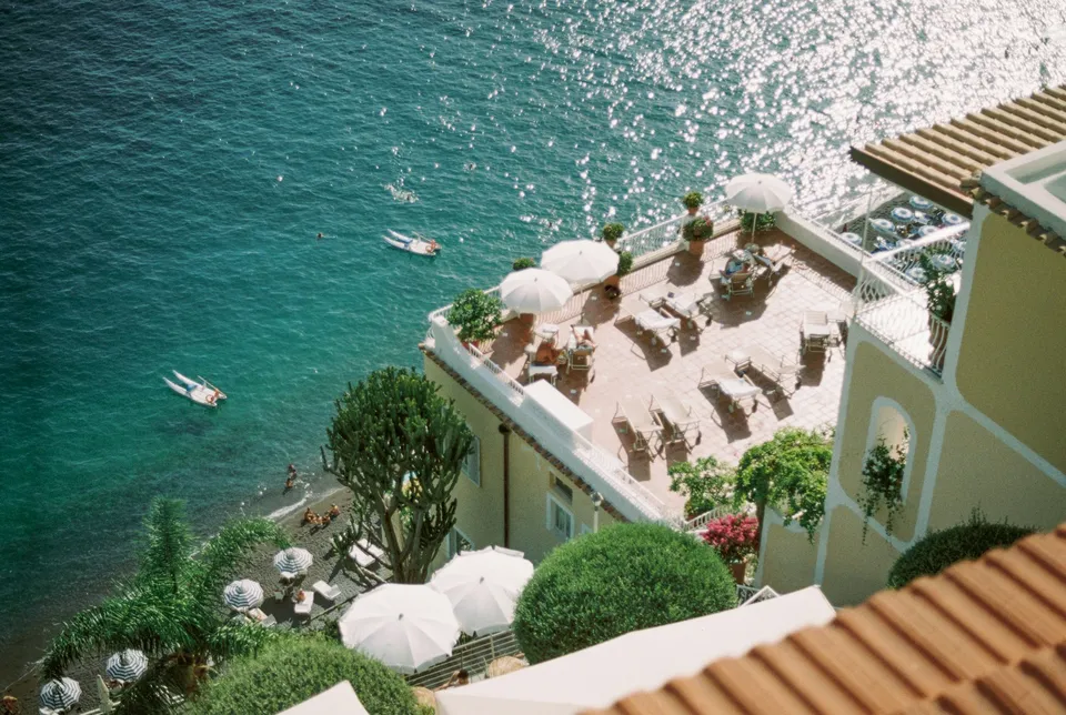 Blick vom Meer auf Positano mit den übereinander gestaffelten Häusern am Hang, der Majolikakuppel und im Hintergrund den Inselchen von Li Galli
