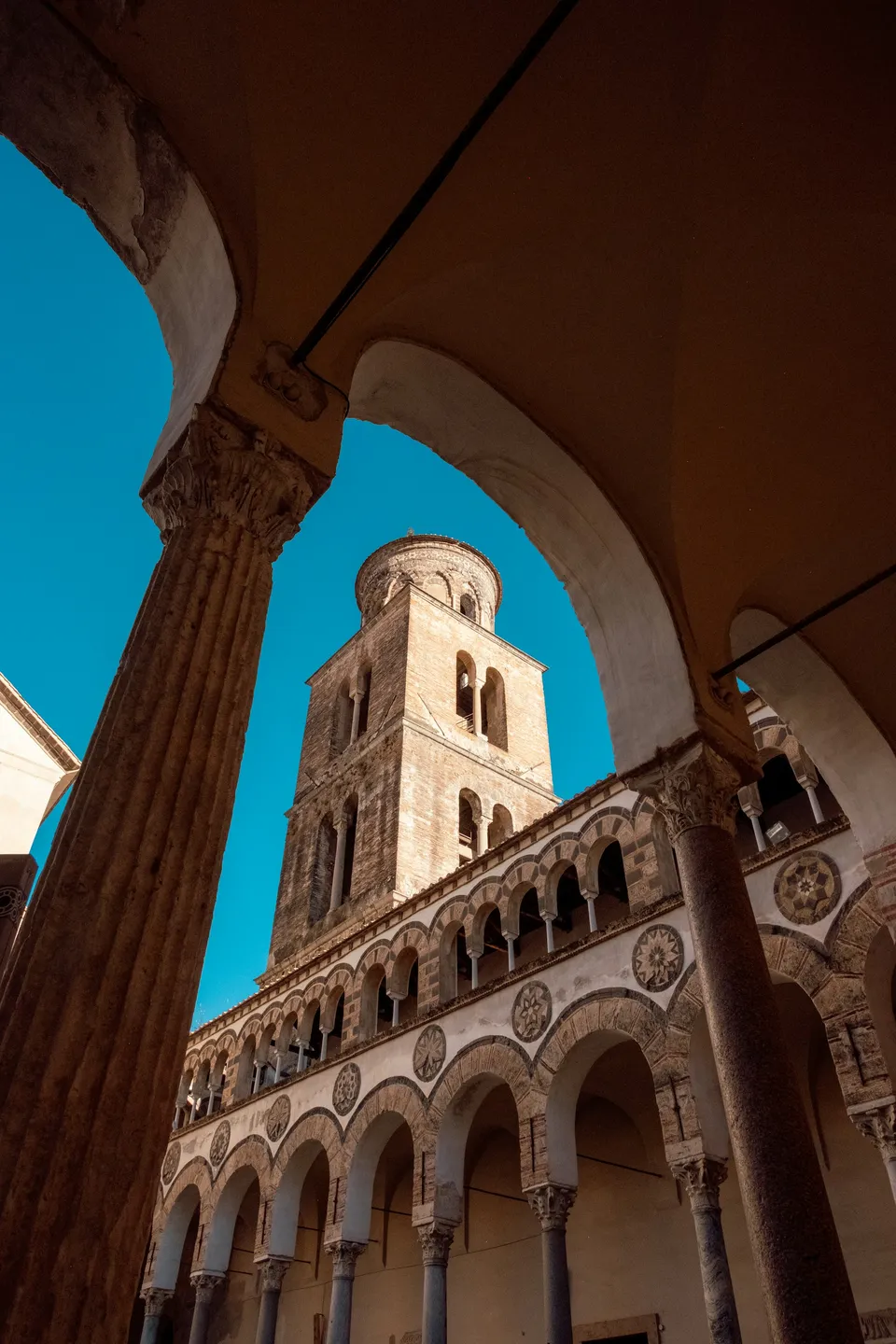 El campanario románico y el atrio porticado del Duomo de San Matteo en el centro histórico de Salerno, con luz dorada